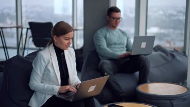 Modern insanlar laptoplarıyla çalışırken rahat rahat koltuklarda oturuyorlar. Ofisteki serbest çalışan mutlu meslektaşlar..