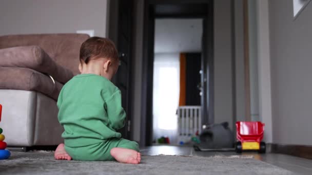 Mały Chłopiec Siedzący Kolanach Podłodze Domu Dziecko Zielonym Stroju Sportowym — Wideo stockowe