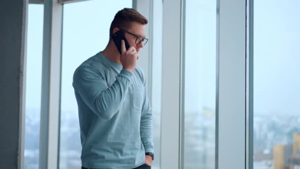 Confident Mature Man Walks Big Window Holding Phone His Ear — Stock Video
