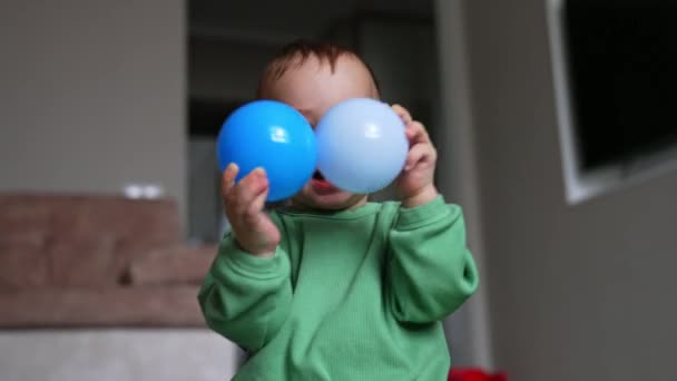 素敵な笑顔のコーカサス人の子供は陽気なプラスチック製のボールで遊んでいます 屋内で床に座っている愛らしい赤ん坊の男の子の遊び — ストック動画