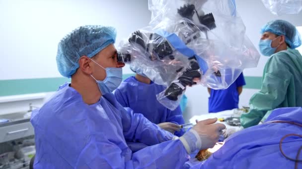 Мужчина Красивый Доктор Маске Смотрит Микроскоп Выполняющий Операцию Два Врача — стоковое видео