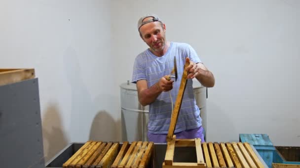 长胡子的成年蚜虫医生用电刀打开蜂蜜框架上的细胞 微笑的男人准备收割蜂蜜 — 图库视频影像