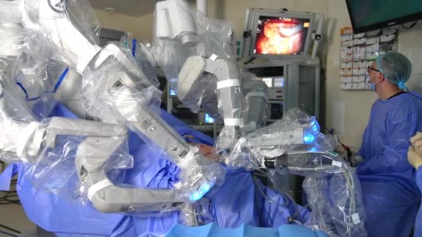 手術室のスクリーンでダ ヴィンチのロボットの仕事を見ている医師 現代の診療所で腹腔鏡手術を行う革新的な機器 — ストック動画