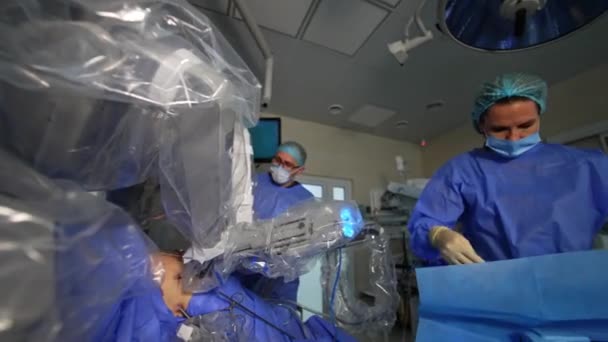 女性医師は ロボットアームから長いノズルをテーブルから取り出し 機械に攻撃します 手術を行うロボットシステム ローアングルビュー — ストック動画