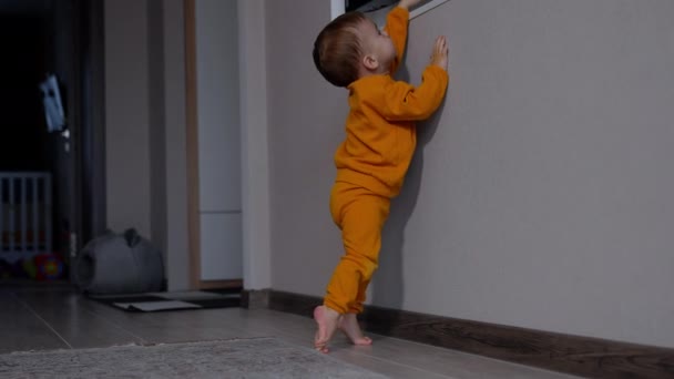 Urocze Dziecko Stojące Zabawkach Próbuje Dosięgnąć Telewizora Wiszącego Ścianie Dzieciak — Wideo stockowe