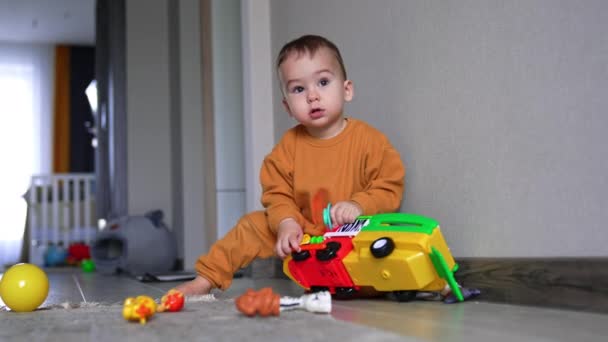 Милый Спокойный Мальчик Играющий Ярким Грузовиком Ребенок Сидит Полу Стены — стоковое видео