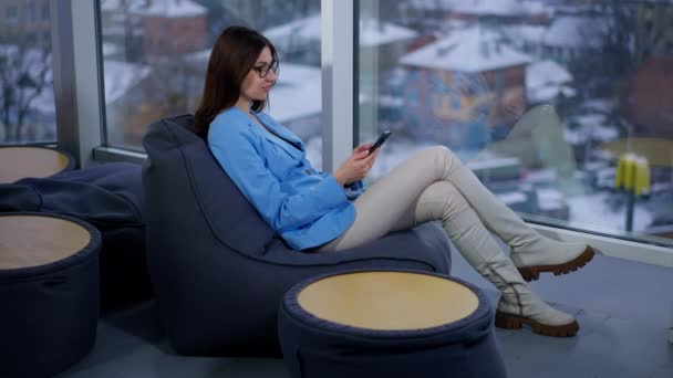 Brunette Sitting Comfortably Relaxed Bean Bag Chair Looking Her Phone — Stock Video