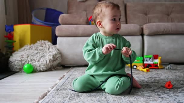 Schöne Kleinkind Spielt Mit Schwarzer Kordel Auf Dem Boden Des — Stockvideo