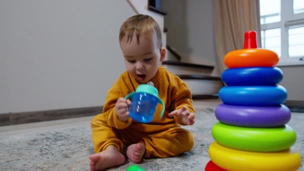 Miły Dzieciak Siedzi Podłodze Przy Wielkiej Piramidzie Zabawkami Dziecko Bierze — Wideo stockowe
