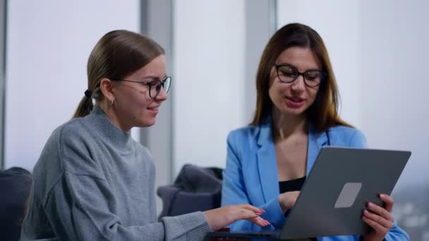女性同事思考一些工作问题或议题 进行讨论 寻找想法或分享这些想法 戴眼镜的女人看着笔记本电脑 积极地交谈着 — 图库视频影像