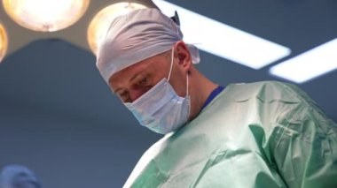 Estetik cerrah ameliyata konsantre oldu. Modern bir klinikte işini yapan bir profesyonelin portresi. Düşük açı görünümü.