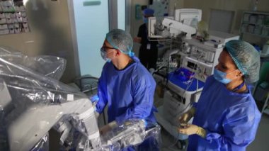 Da Vinci robotik sisteminin operasyon alanında duran iki sağlık görevlisi. İlgili doktorlar ameliyathanedeki monitöre bakarlar. Üst görünüm.