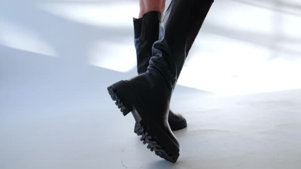 平底牵引机鞋底上的高黑色皮靴 裸露在女性腿上 在轻工作室展示鞋子的模型 — 图库视频影像