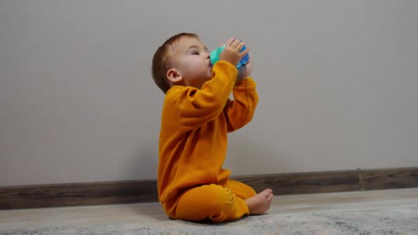 Μικρό Χαριτωμένο Μωρό Κάθεται Στο Πάτωμα Κρατά Μπουκάλι Και Ποτά — Αρχείο Βίντεο