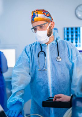 Yoğun bakım ünitesinde koruyucu giysili ve maskeli bir doktor..