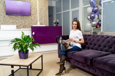 Güzel bayan dergiyle oturuyor. Genç kadın poz veriyor ve dinleniyor.