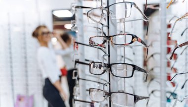 Gözlükçülerde sıra sıra gözlük. Gözlük dükkanı. Optik mağazasında gözlüklü dur. Kadınlar gözlüğü seçer. Görme düzeltmesi.