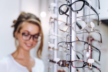 Genç kadın gözlükçüde gözlük test ediyor..