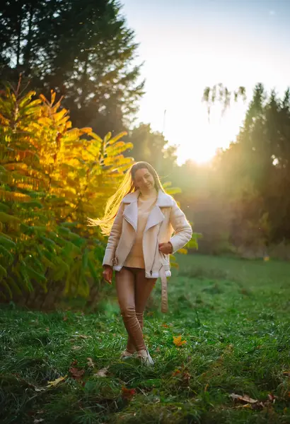 Young woman is walking through field at sunset, young woman is walking through field at sunset.