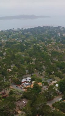 Okyanusun sisli sularında, deniz kıyısındaki yeşil deniz kenti Carmel. Sis ufuk çizgisini hava perspektifinden kaplıyor. Dikey video.