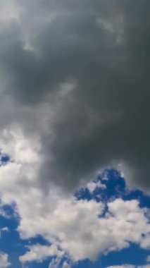 Yumuşak kabarık bulutlar hızla şekil değiştiriyor. Bulutların arasından geçen güneş ışınları. Zaman ayarlı. Dikey video.