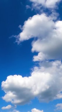 İnanılmaz mavi gökyüzü ve küçük bulutlar arasında uçuyor. Tüylü bulutların dönüşümünün güzel zamanı. Dikey video.