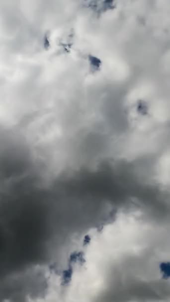 青い空を完全に覆っている灰色の雲 明るい太陽が雲を通り抜けている タイムラプス バーティカルビデオ — ストック動画