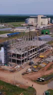 Tahıl ambarı bölgesinde inşaat alanı. Endüstriyel kompleksin gelecekteki kısmı için yeni bina. Arka planda yeşil alanlar ve ormanlar var. Dikey video.