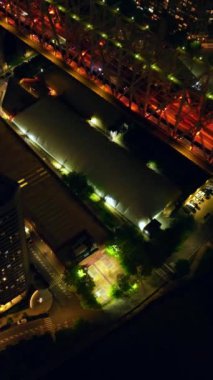 Güzel ışıklandırılmış ada ve köprünün geçişi. Geceleri köprünün yanından çok sayıda araba geçiyor. Sihirli New York tepeden. Dikey video.