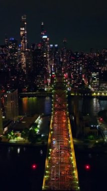 Muhteşem Queensboro köprüsü küçük ada ve East River 'ı geçiyor. Gece vakti New York 'un inanılmaz manzarası. Dikey video.
