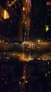 New York binalarının çatılarına bakıyorum. Geceleri New York 'un aydınlık caddelerinde yoğun trafik var. Dikey video.