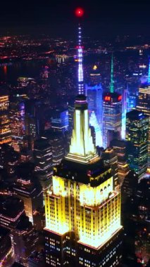 Empire State Binası 'nın çatısı gece parlak sarı ışıkla aydınlatılmış. New York Panorama 'nın arka planında muhteşem bir gökdelen. Dikey video.