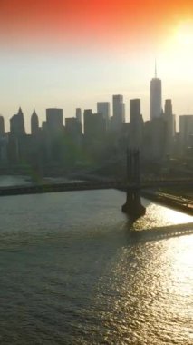 New York 'un Doğu Nehri üzerindeki güzel köprüleri. İnanılmaz gökdelenler pembe gökyüzüne ve batan güneşe karşı. Dikey video.
