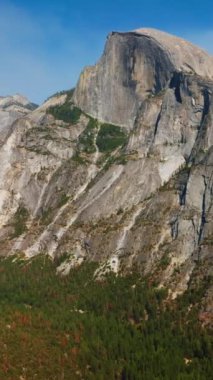 Yosemite, California 'nın büyük dağları, parlak güneş ışınları altında ABD. Kayaların dibinde büyüyen yeşil orman. Dikey video.