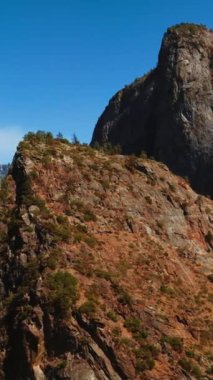 Yosemite Ulusal Parkı, Kaliforniya, ABD 'deki dağların nefes kesici manzarası. Gökyüzünün masmavi zemininde muhteşem kayalar ve uçurumlar. Dikey video.
