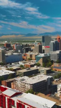 Çeşitli mimarisi olan Sunny Salt Lake City. Arka planda kayaların olduğu şehir panoraması. Havadan bakış açısı. Dikey video.