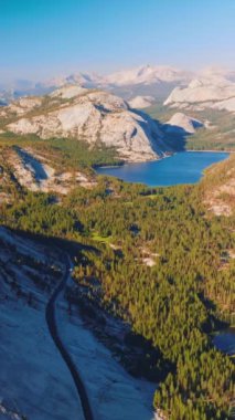 Yosemite Ulusal Parkı 'nın parlak güneş ışınları altında manzarası. Güzel kayalar, çam ağaçları ve göl manzaralı ünlü parkın manzarasında. Dikey video.