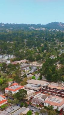 Kaliforniya 'nın deniz kıyısındaki sevimli Carmel şehri. Arkasında dağlar olan yeşil şehir manzarası. Üst Manzara. Dikey video.