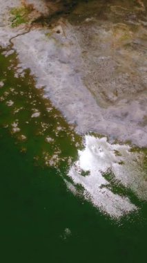 Kaliforniya, ABD 'deki Mono Gölü' nün yeşil ve mavi suları. Gölün çıplak kıyısı tuz tabakasıyla kaplıydı. Üst Manzara. Dikey video.