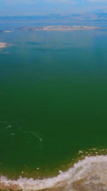Mono Gölü panoraması tuzlu kıyılarla çevrili. Gölün gök mavisi ufukta mavi gökyüzü ile birleşiyor. Üst Manzara. Dikey video.