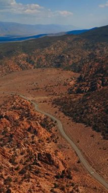 Kayalık kayalıkların ve ıssız arazilerin arasından geçen otoyol. Nevada dağlarındaki güneşli bir gün görüntüsü. Dikey video.