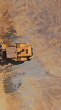 Yol yapım aşamasında. İnşaat alanında çalışan ağır makinenin üst görünümü Dikey video.