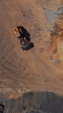 Kazı makinesi kumlu yüzeyde çalışıyor. İnşaat sahasında çalışan ağır toprak taşıyıcının hava üst görünümü.