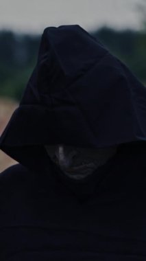 Sahada hayalet figürü var. Siyah pelerinli hayalet dikey videoda yürüyor.