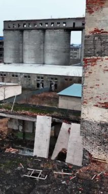 Bombalanan binalarda çıplak tuğla duvarlar ve pencere delikleri. Hava saldırısından kaynaklanan yıkılmış mimari. İHA atışı. Dikey video.