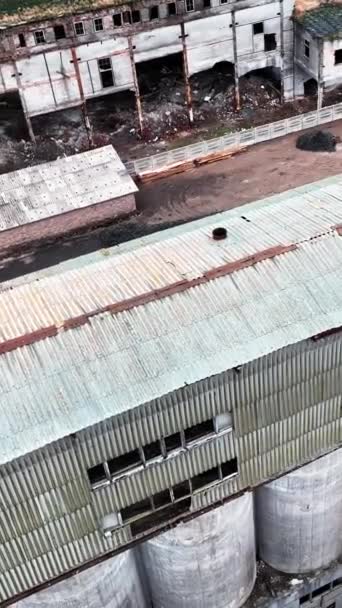 化学プラントの古い破片 地面に大きな穴と破片が付いている壊れた壁 空からの眺め バーティカルビデオ — ストック動画