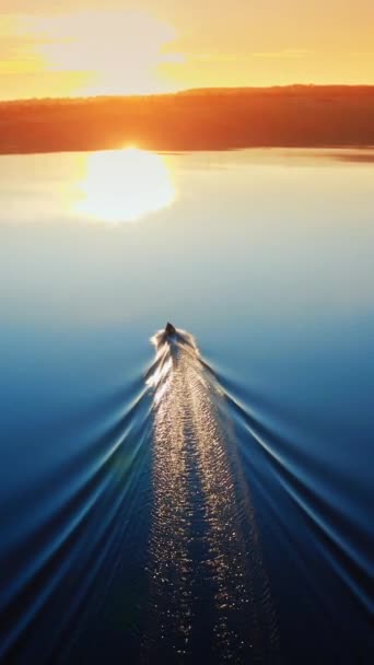 日没時の風景を眺める カメラは日没の垂直ビデオに向かって川を航行するボートに続きます — ストック動画
