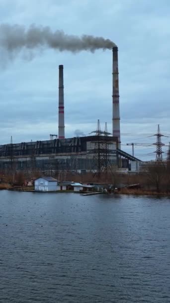 在河岸的空气中升起两个大水槽的工业厂房 黑烟从烟囱里冒出来 鸭子在河的上游漂浮着 垂直录像 — 图库视频影像