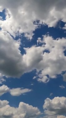 Gündüz vakti bulut oluşumu. Mavi gökyüzünde şekil değiştiren güzel hafif pamuk bulutları. Zaman ayarlı. Dikey video.