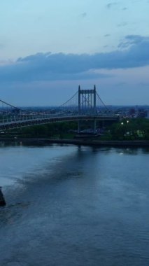 East River 'da yüzen feribot. Güzel Triborough Köprüsü 'nün altından geçen bir nakliye aracı. New York 'ta akşam vakti. Dikey video.